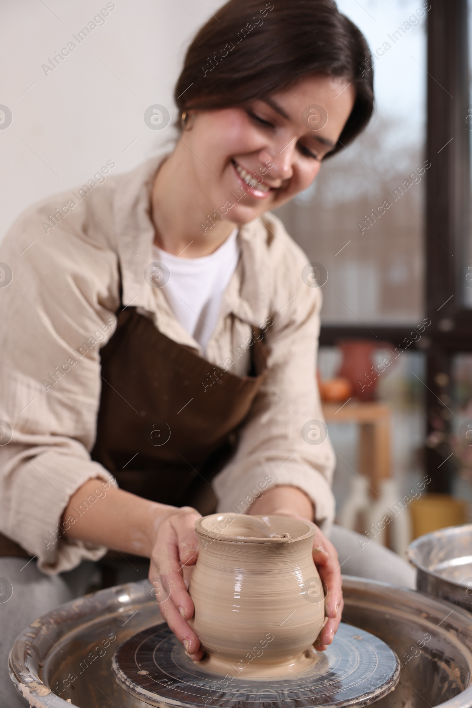 Photo of Hobby and craft. Smiling woman making pottery indoors, selective focus