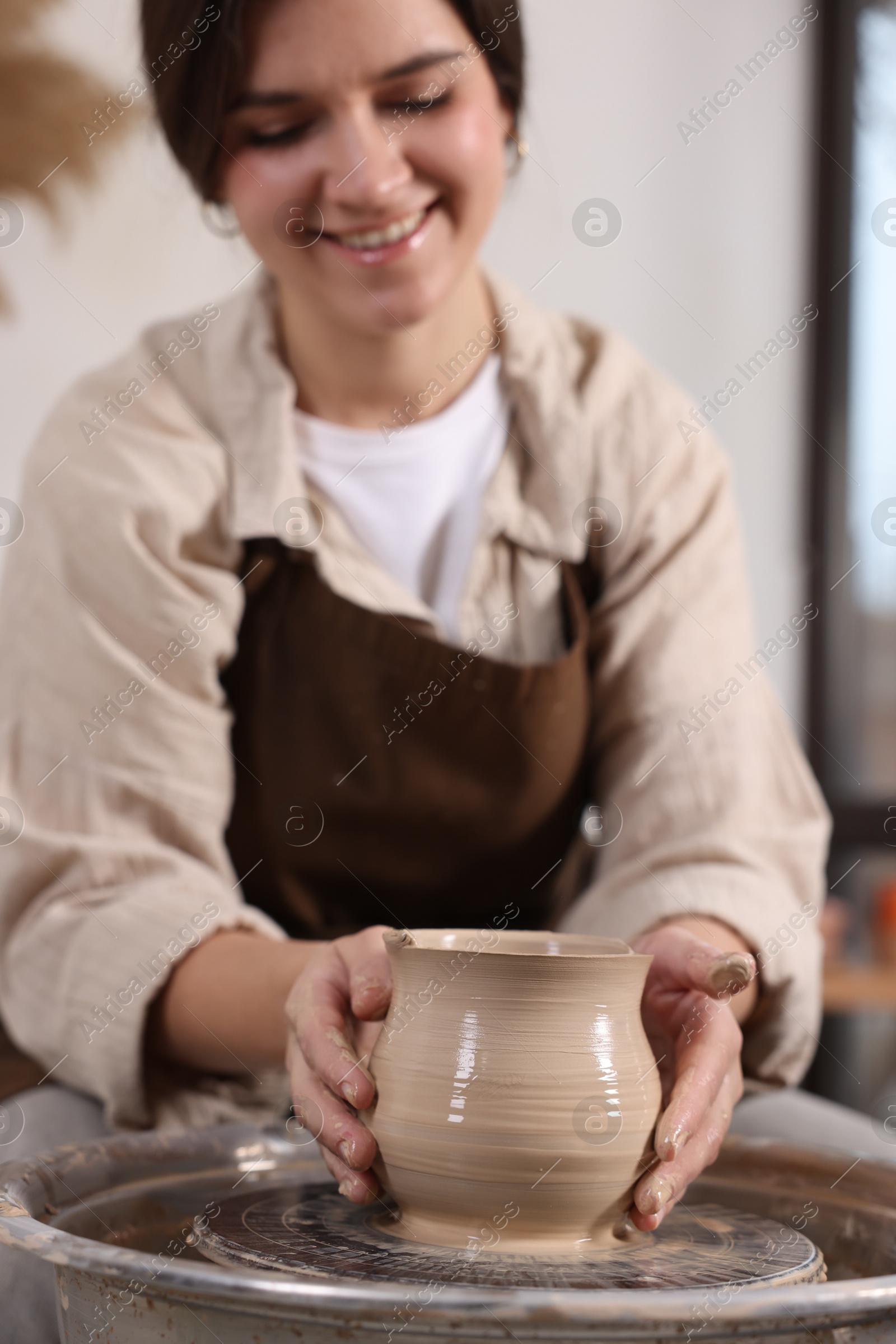 Photo of Hobby and craft. Smiling woman making pottery indoors, selective focus