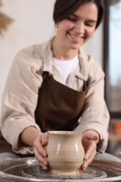 Photo of Hobby and craft. Smiling woman making pottery indoors, selective focus