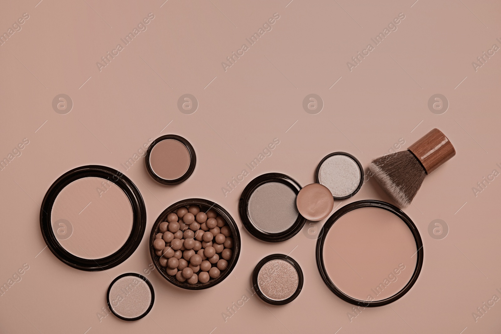 Image of Makeup products in mocha mousse shades on dark beige background, flat lay. Trendy color of 2025 year