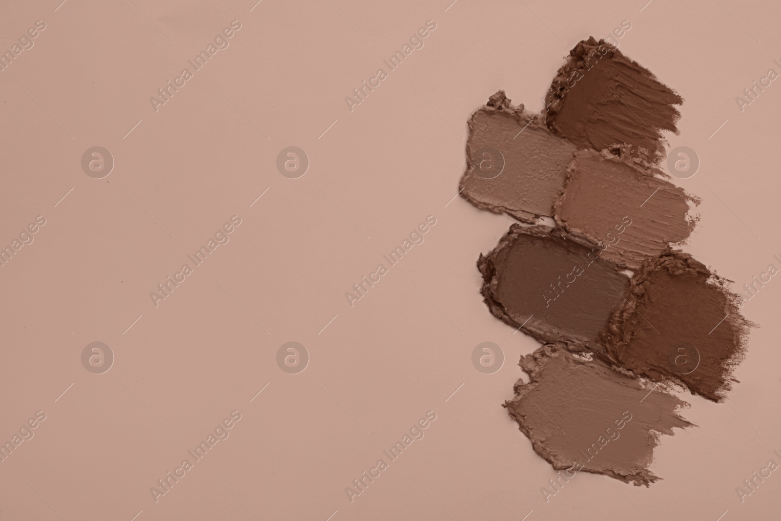 Image of Lipstick samples in mocha mousse shades on dark beige background, top view. Trendy color of 2025 year