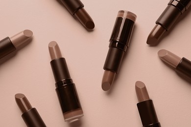 Image of Lipsticks in mocha mousse shades on dark beige background, top view. Trendy color of 2025 year