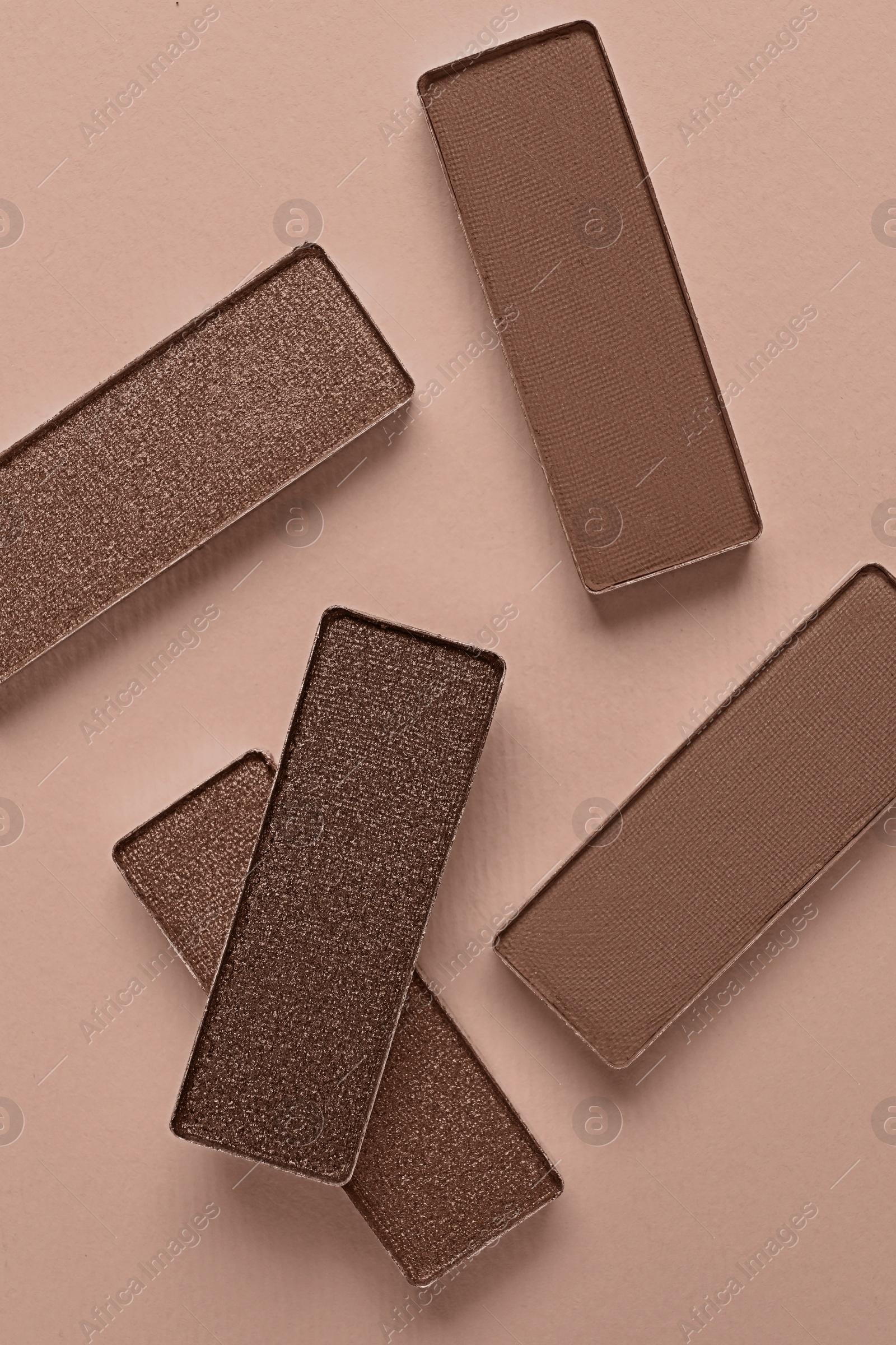 Image of Eyeshadows in mocha mousse shades on dark beige background, top view. Trendy color of 2025 year