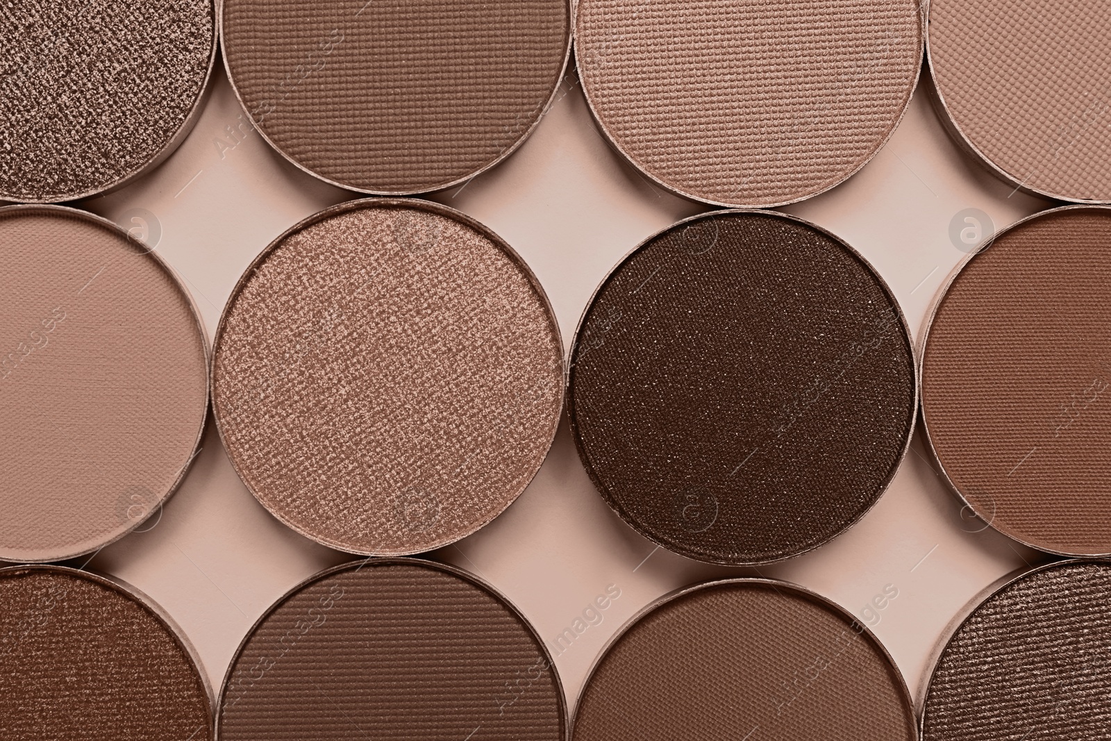 Image of Eyeshadows in mocha mousse shades on dark beige background, flat lay. Trendy color of 2025 year