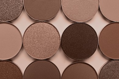 Image of Eyeshadows in mocha mousse shades on dark beige background, flat lay. Trendy color of 2025 year