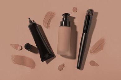 Image of Liquid foundations in mocha mousse shades and makeup brush on dark beige background, flat lay. Trendy color of 2025 year