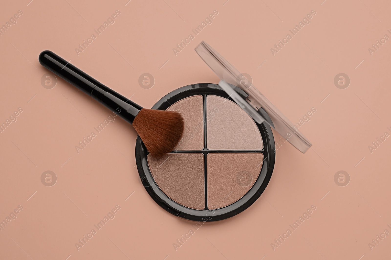 Image of Eyeshadow palette in mocha mousse shades and makeup brush on dark beige background, top view. Trendy color of 2025 year