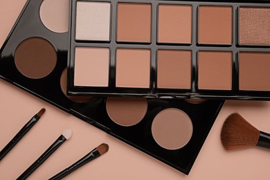 Image of Eyeshadow palettes in mocha mousse shades and makeup brushes on dark beige background, top view. Trendy color of 2025 year