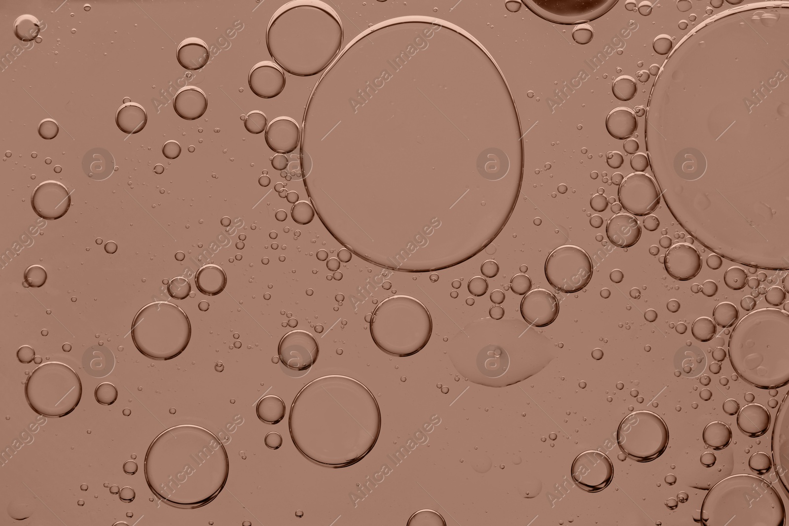 Image of Cosmetic oil on mocha mousse shade background, macro view. Trendy color of 2025 year