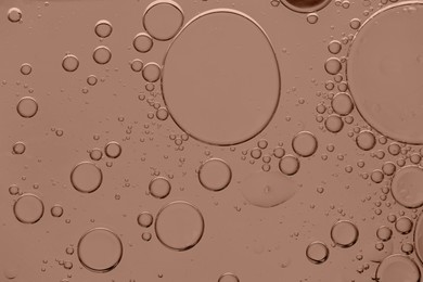 Image of Cosmetic oil on mocha mousse shade background, macro view. Trendy color of 2025 year