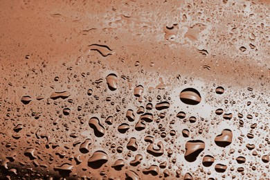 Image of Water drops on glass surface, closeup. Toned in trendy color of 2025 year - mocha mousse