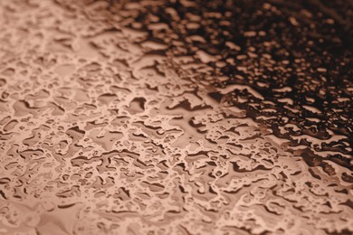 Image of Water drops on glass surface, closeup. Toned in trendy color of 2025 year - mocha mousse