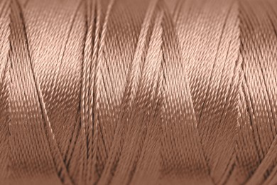 Image of Sewing thread in mocha mousse shade, closeup. Trendy color of 2025 year