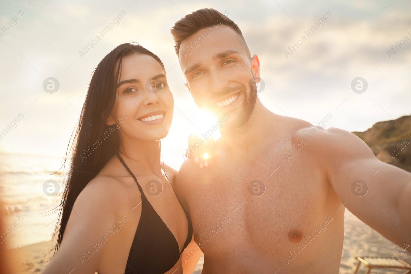 Photo of Happy young couple taking selfie on beach at sunset