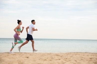 Photo of Couple running together on beach, space for text. Body training