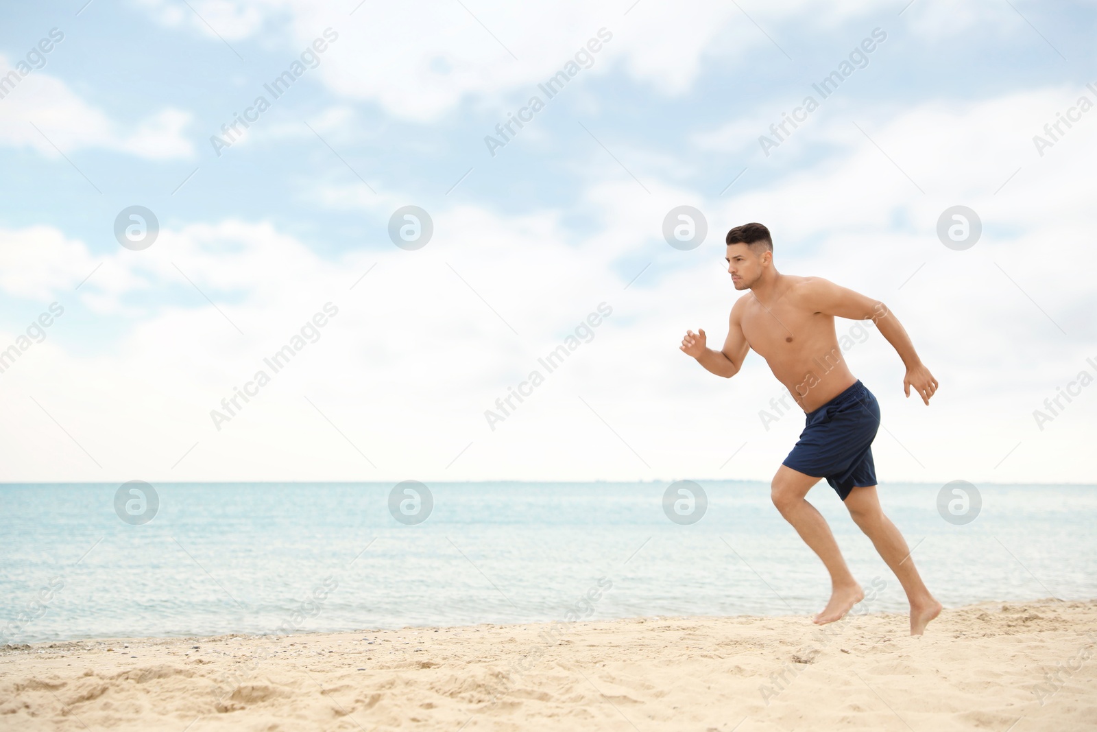 Photo of Muscular man running on beach, space for text