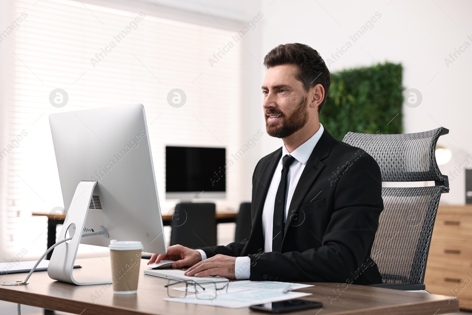 Photo of Man working on computer at table in office