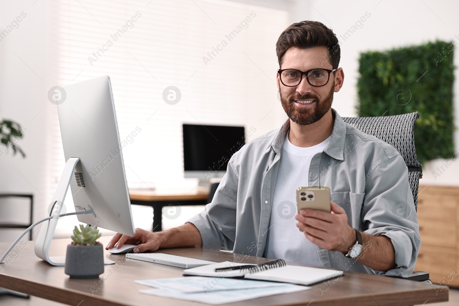 Photo of Man with smartphone working at table in office