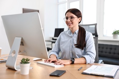 Photo of Woman working on computer at table in office