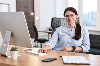 Photo of Portrait of woman at table with computer in office