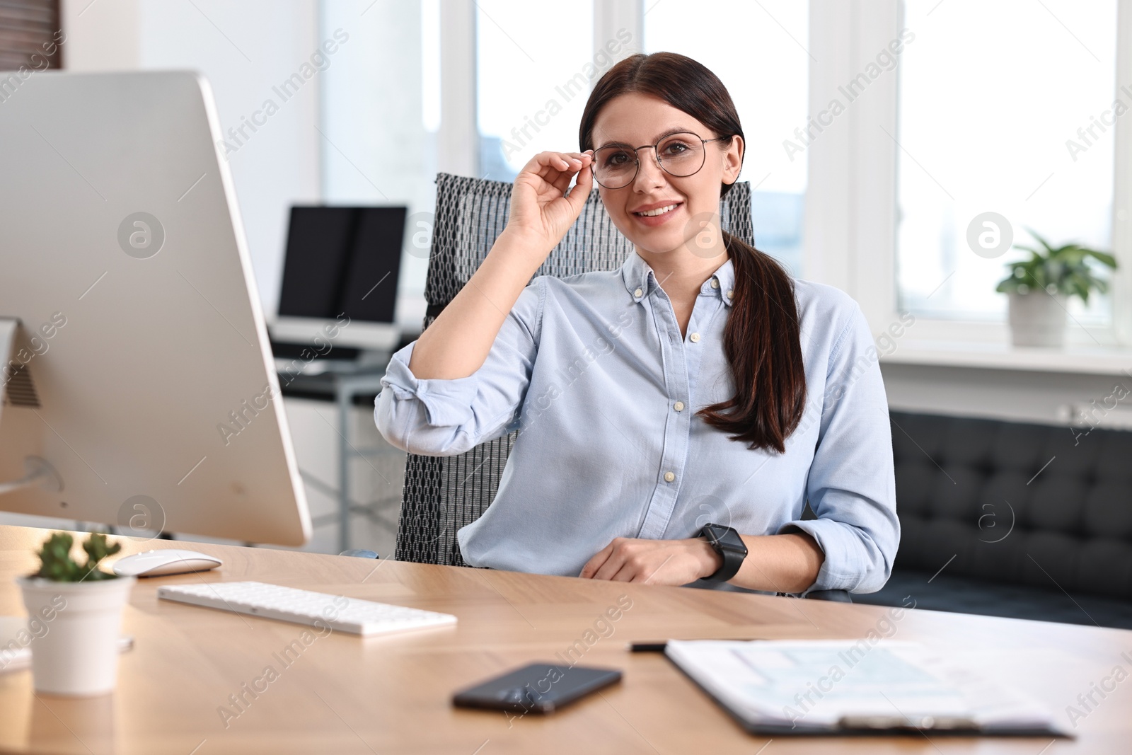 Photo of Portrait of woman at table with computer in office