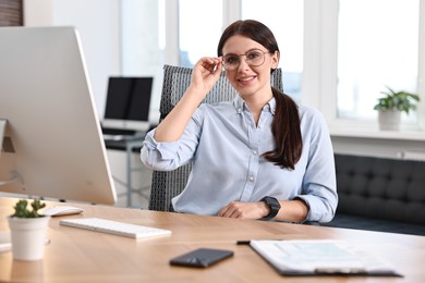 Photo of Portrait of woman at table with computer in office