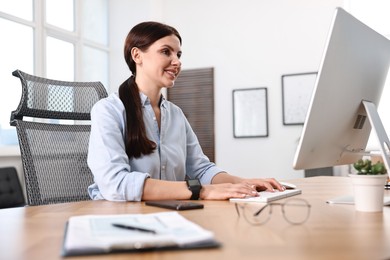 Photo of Woman working on computer at table in office