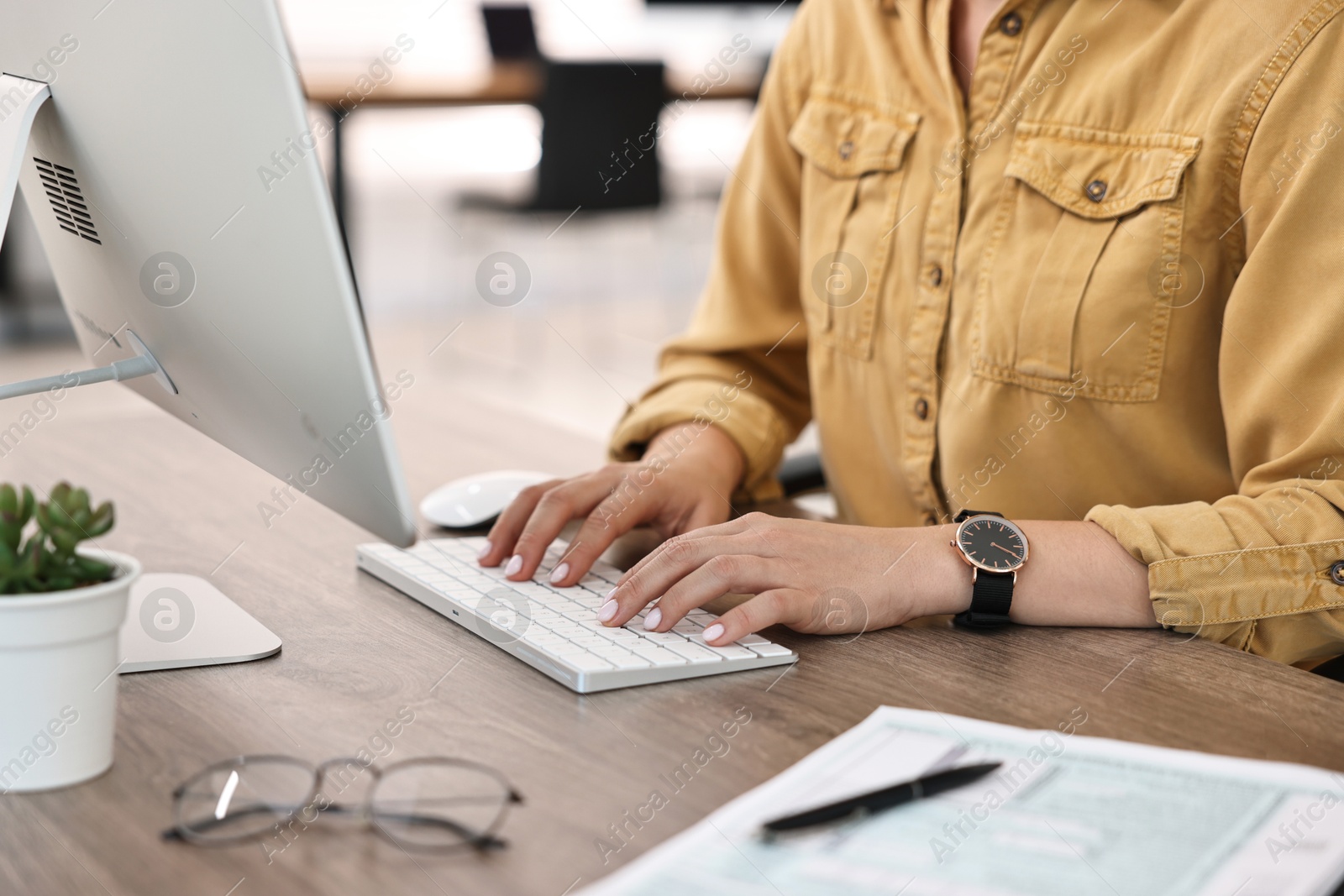 Photo of Woman working on computer at table in office, closeup