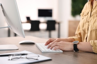 Photo of Woman working on computer at table in office, closeup