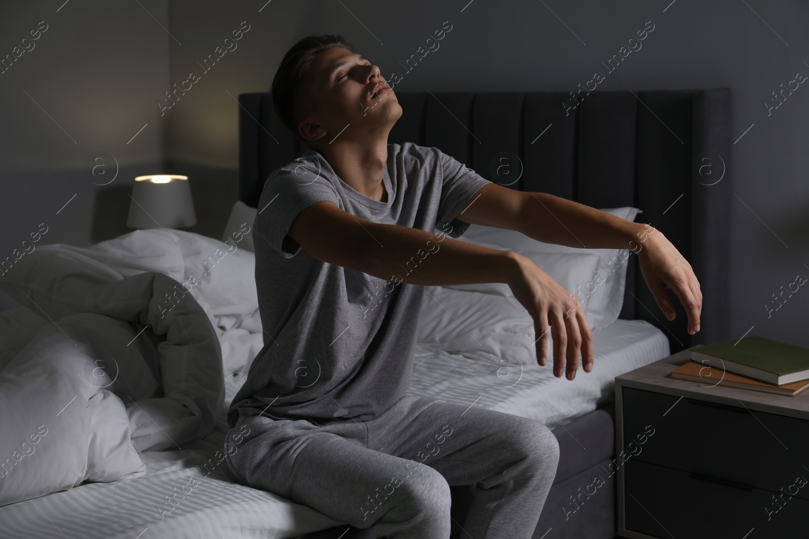 Photo of Young man suffering from sleepwalking on bed at home