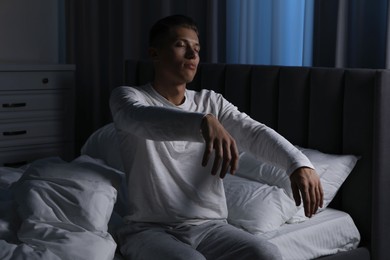 Photo of Young man suffering from sleepwalking on bed at home