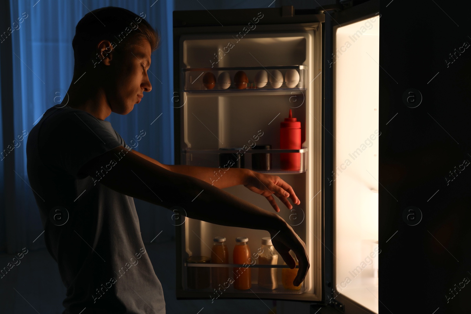 Photo of Young man suffering from sleepwalking near fridge at home