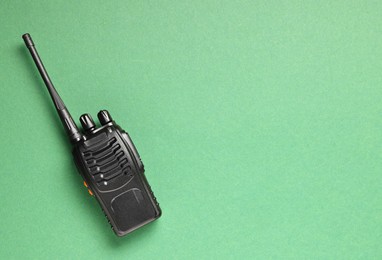 Photo of One walkie talkie on green background, top view. Space for text