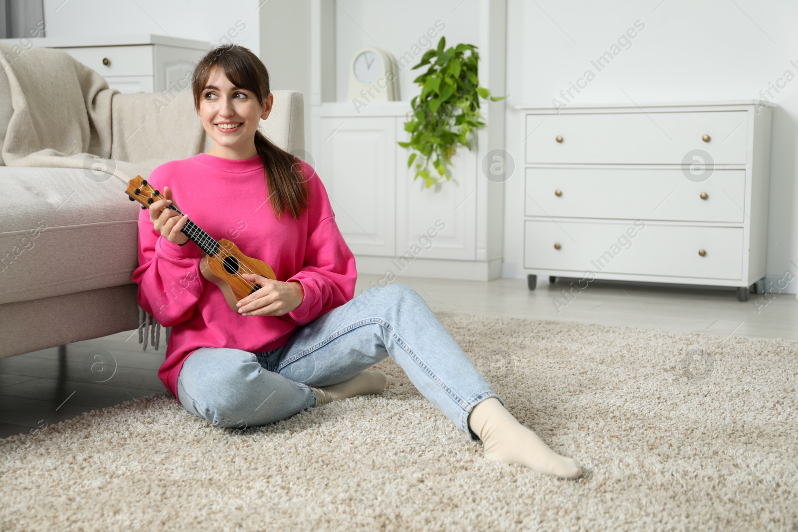 Photo of Happy woman playing ukulele on floor at home