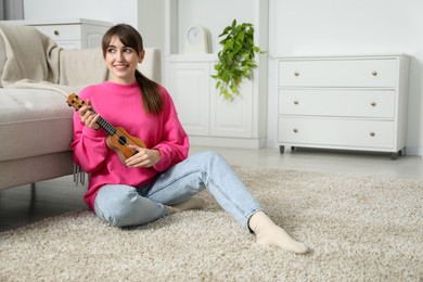 Photo of Happy woman playing ukulele on floor at home