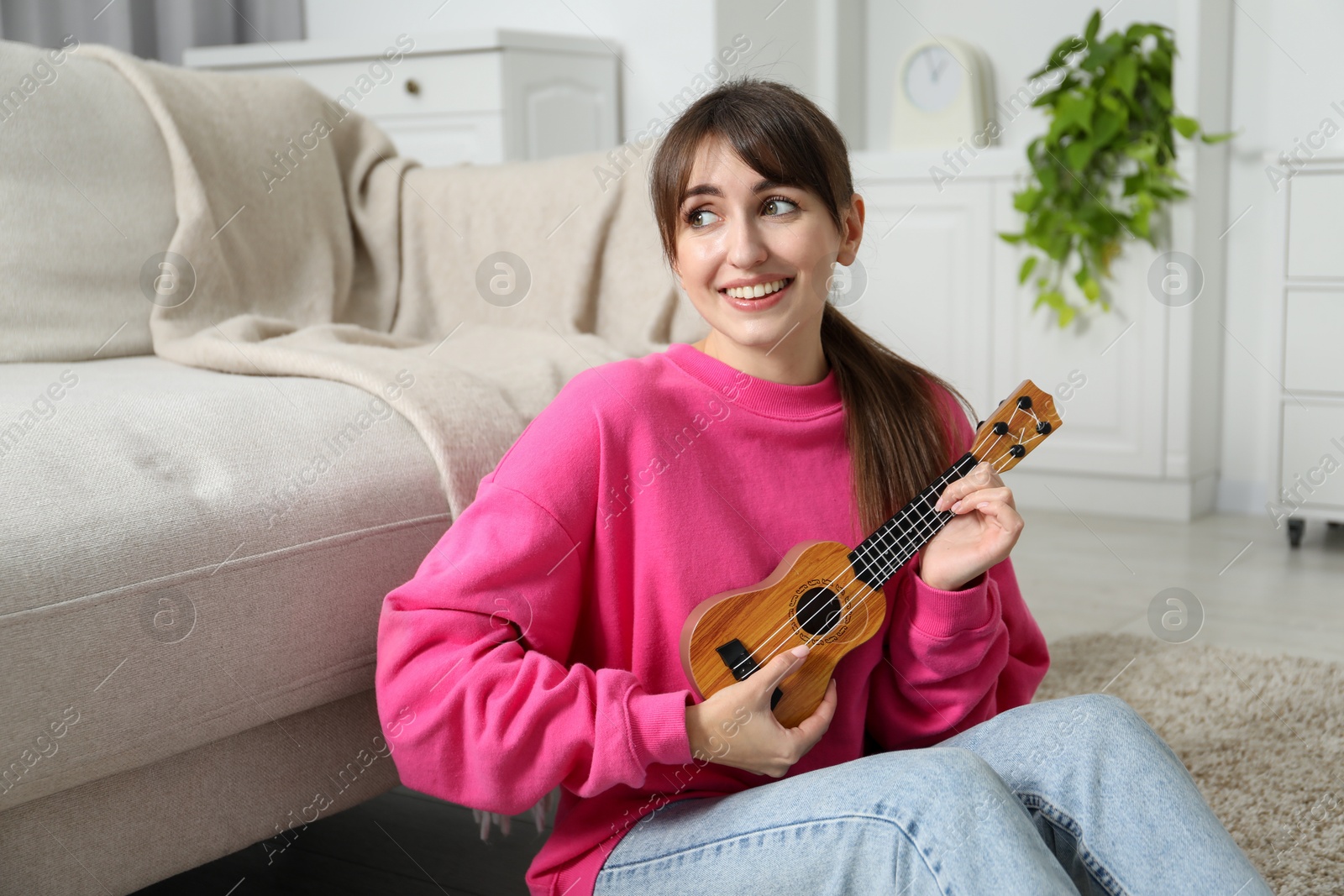 Photo of Happy woman playing ukulele on floor at home