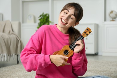 Photo of Happy woman playing ukulele on floor at home