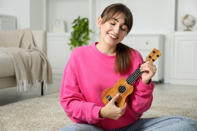 Photo of Happy woman playing ukulele on floor at home