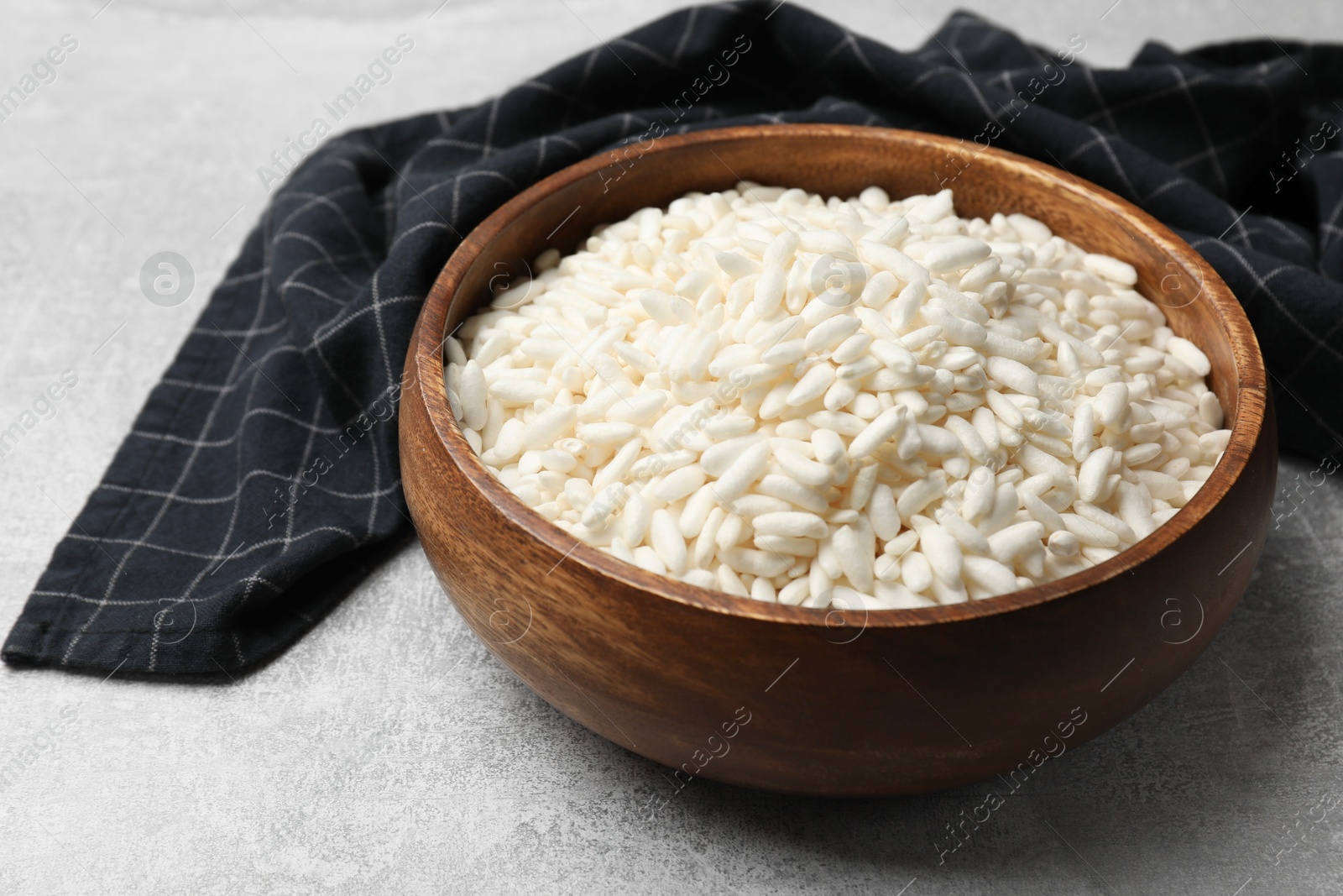 Photo of Puffed rice in bowl on light grey table, closeup