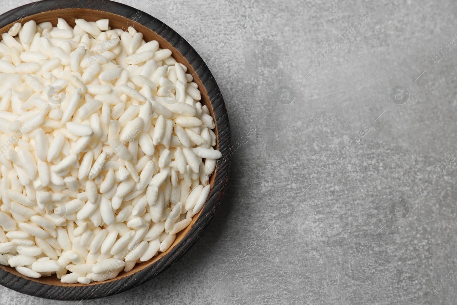 Photo of Puffed rice in bowl on light grey table, top view. Space for text