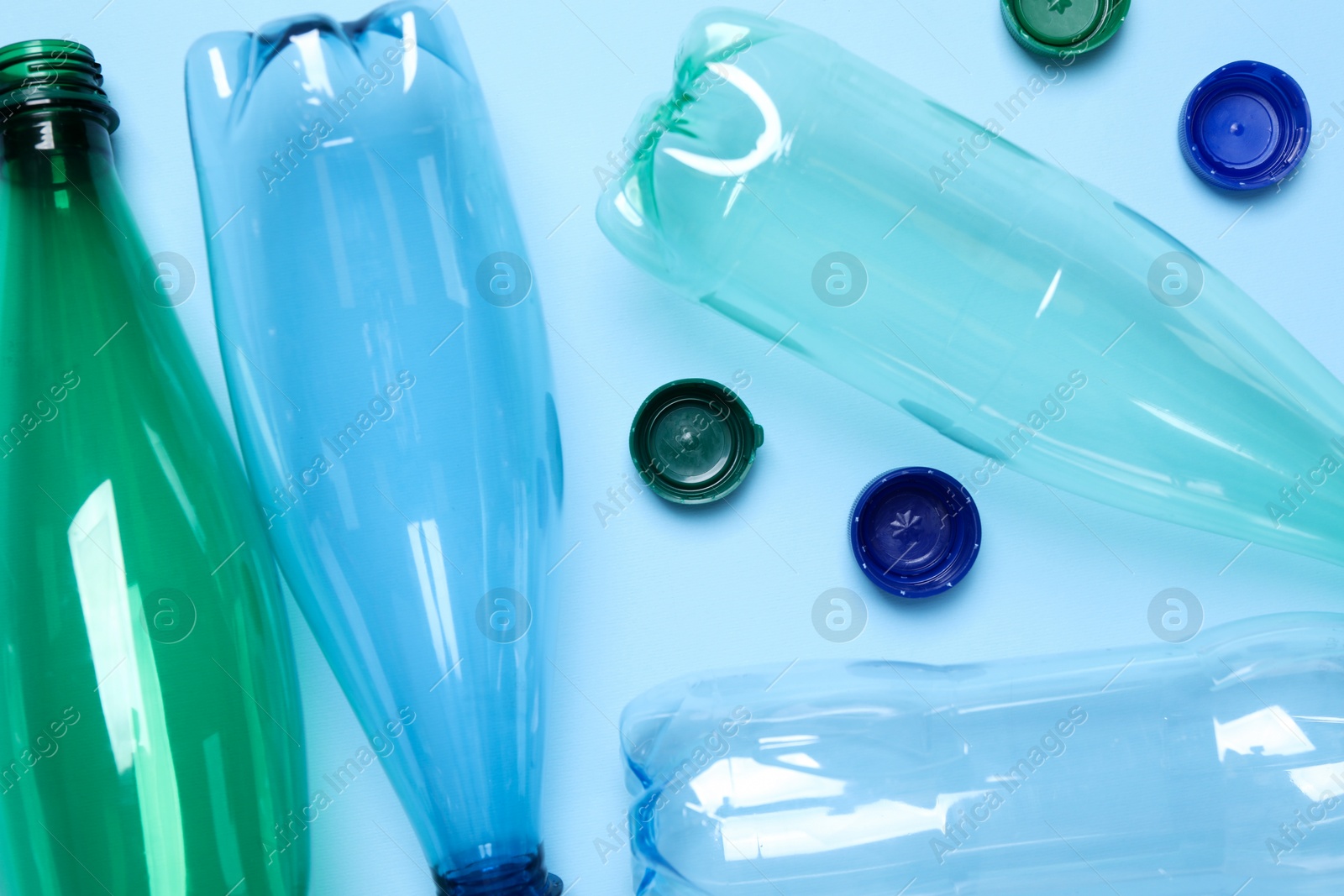 Photo of Empty plastic bottles on light blue background, flat lay