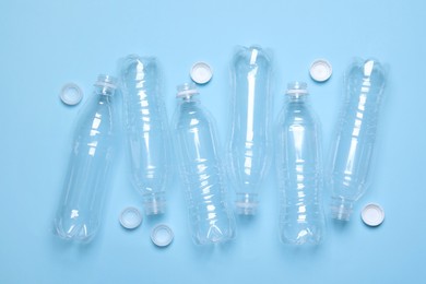 Photo of Empty plastic bottles on light blue background, flat lay