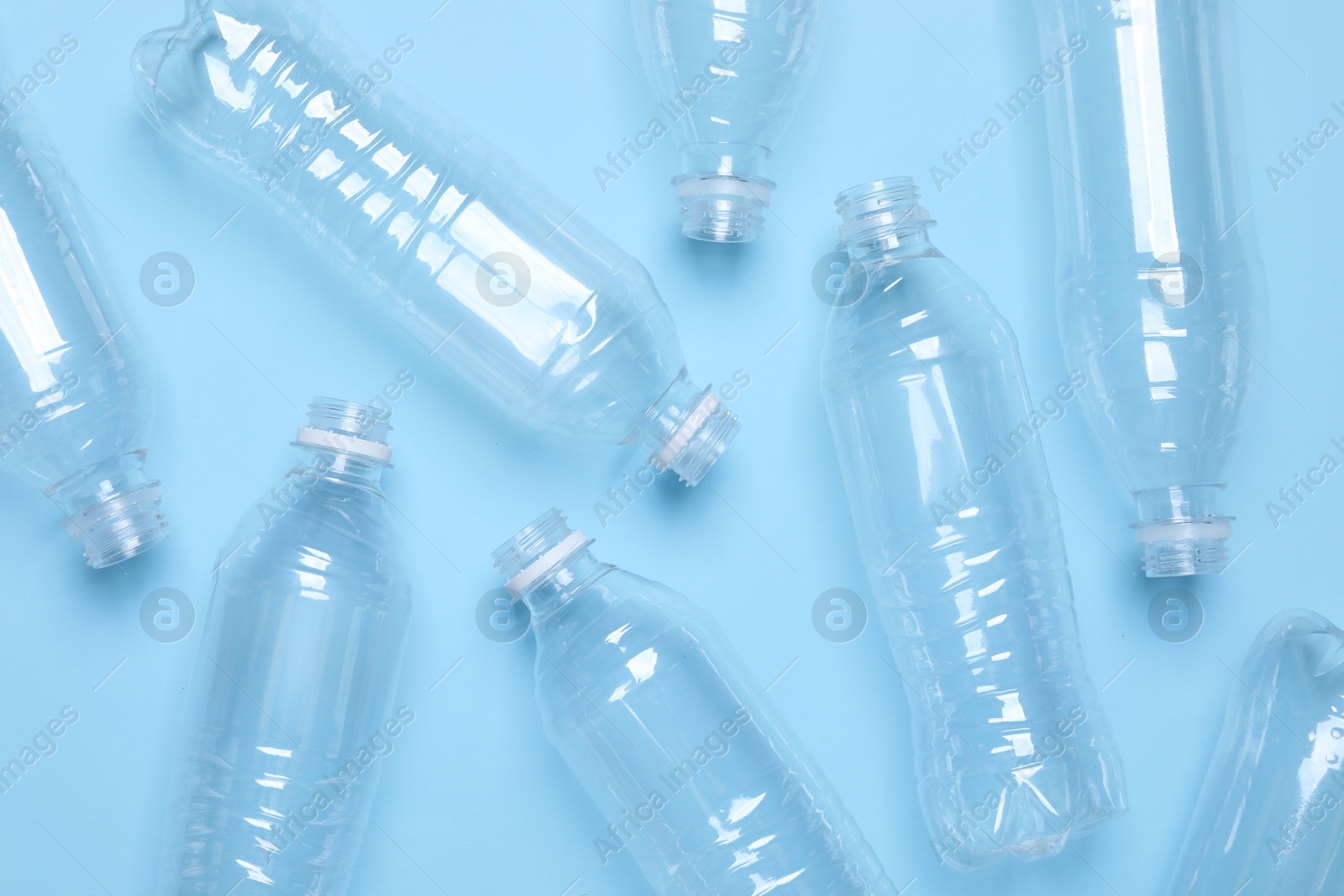 Photo of Empty plastic bottles on light blue background, flat lay