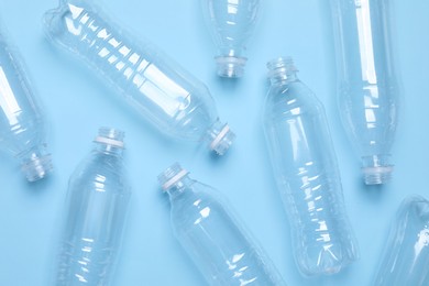 Photo of Empty plastic bottles on light blue background, flat lay