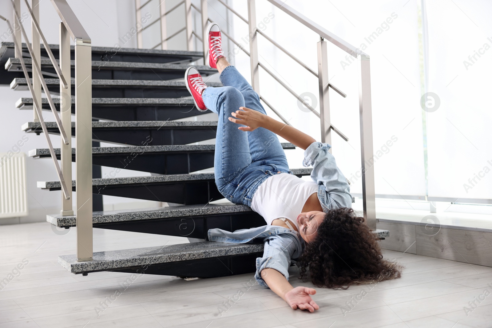 Photo of Injured woman on stairs in building after fall. Dangerous accident