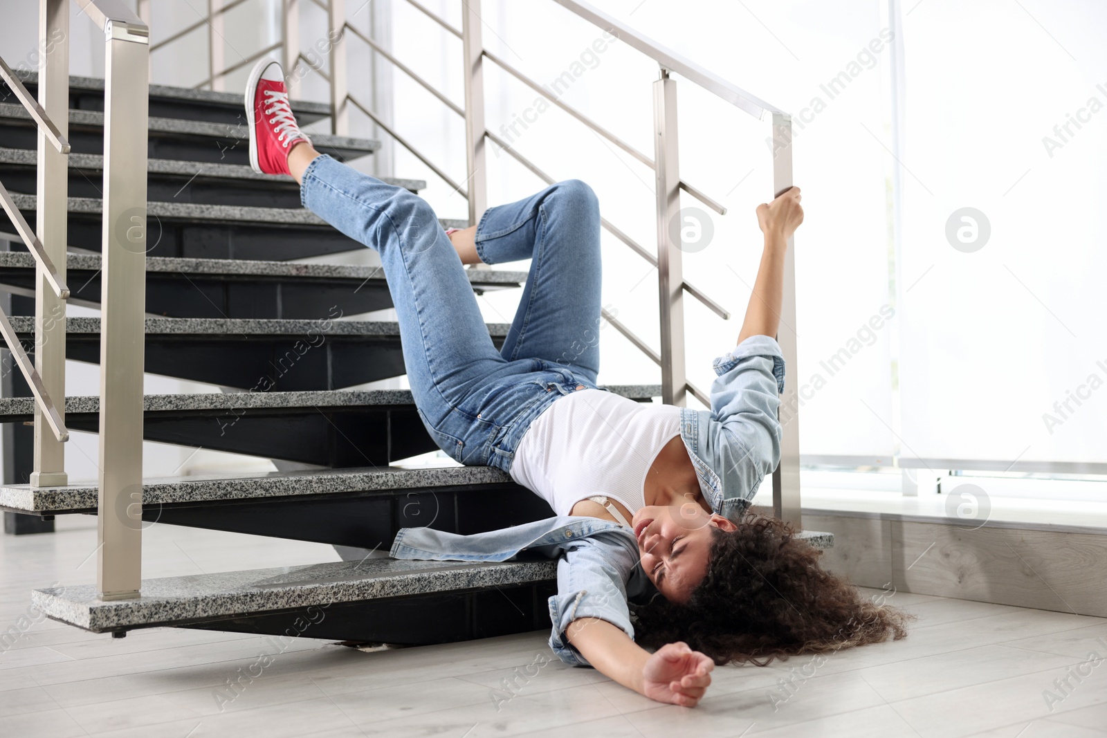 Photo of Injured woman on stairs in building after fall. Dangerous accident