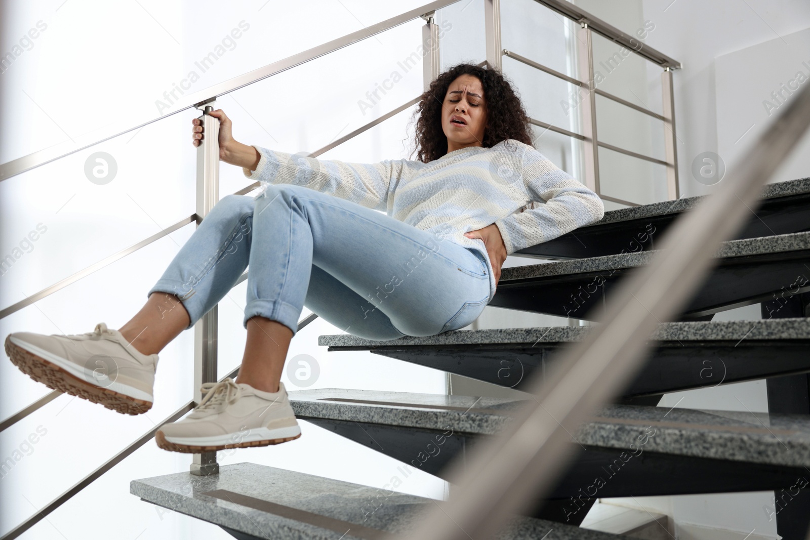 Photo of Injured woman on stairs in building after fall. Dangerous accident