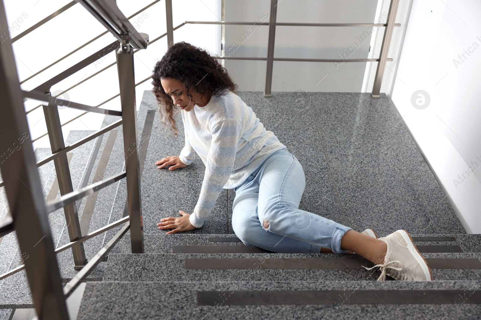 Photo of Injured woman on stairs in building after fall. Dangerous accident