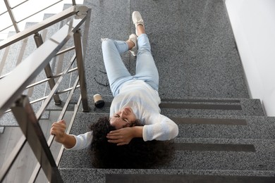 Photo of Woman with injured head on stairs in building after fall, above view. Dangerous accident