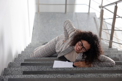 Photo of Injured woman on stairs in building after fall. Dangerous accident